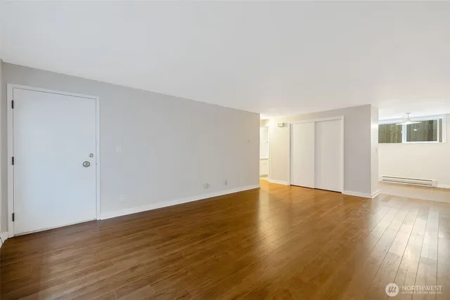 a view of an empty room with wooden floor and a window