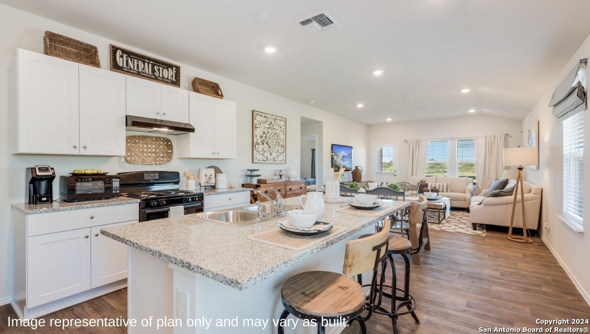 14671 Clay Rdg Run San Antonio, TX 78253 - Photo 6 of 42 a kitchen with a table chairs stove and white cabinets