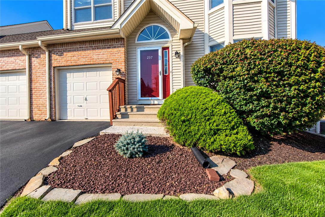 An inviting entryway presents a vibrant front door alongside a neat brick and vinyl facade.