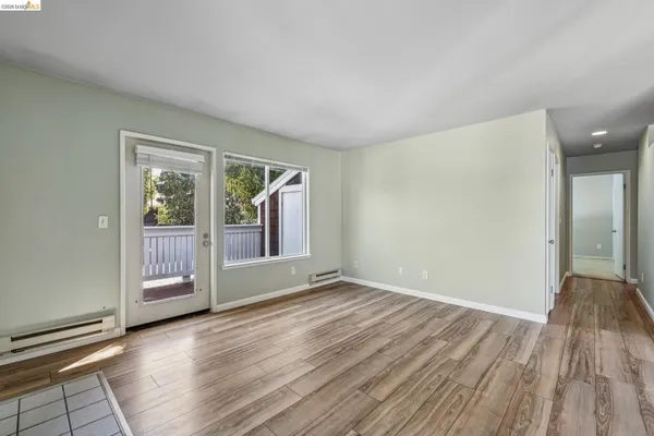 a view of an empty room with a window and wooden floor