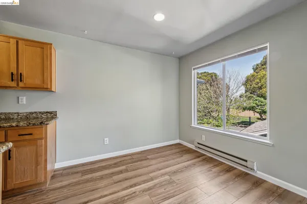 an empty room with wooden floor cabinet and windows