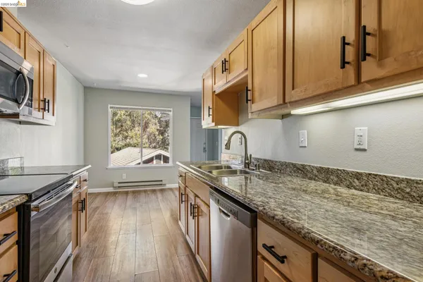 a kitchen with granite countertop a sink stove and cabinets
