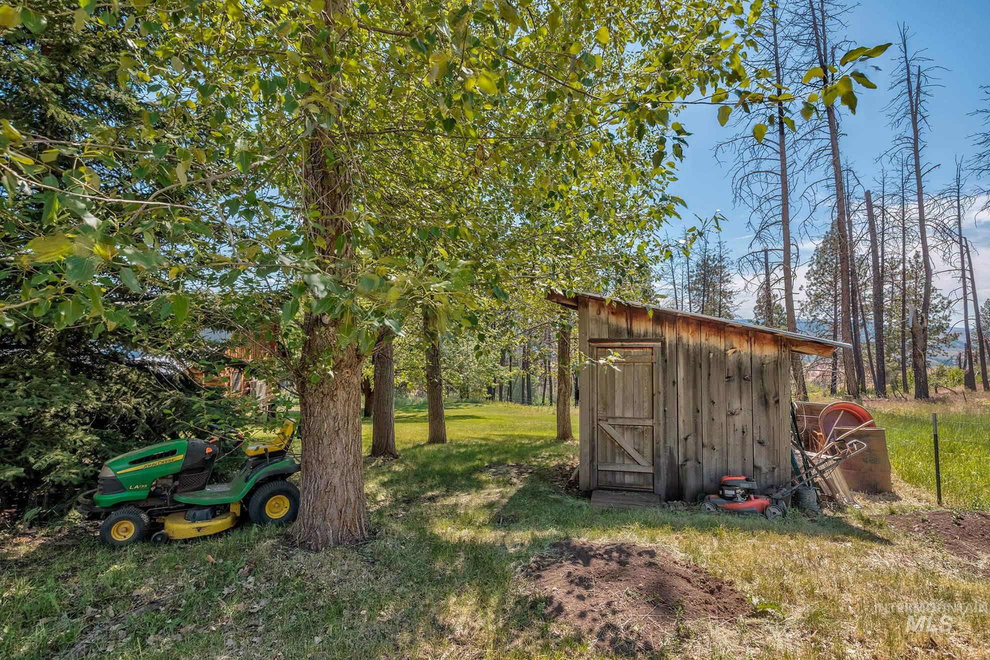 2150 Seid Creek Road Cambridge, ID 83610 - Photo 31 of 50 Rustic wooden shed with corrugated metal roofing, surrounded by mature trees and natural landscaping
