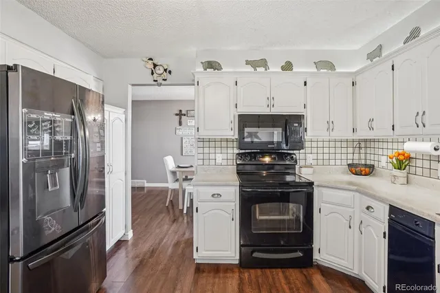 a kitchen with cabinets stainless steel appliances a sink and wooden floor