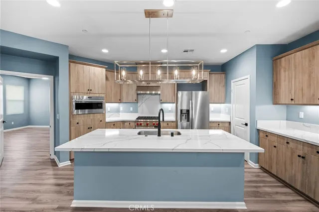 a kitchen with kitchen island a counter space a sink appliances and cabinets
