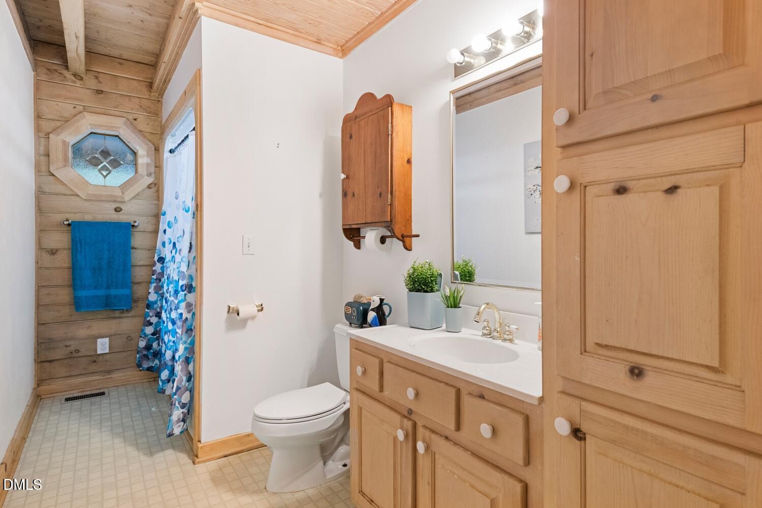 7391 Howerton Road Elon, NC 27244 - Photo 28 of 53 Wood-paneled ceiling, wood-finish walls, built-in cabinetry, vanity with integrated sink, and octagonal decorative window