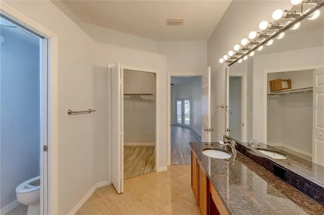 a spacious bathroom with a granite countertop sink a toilet and a large mirror