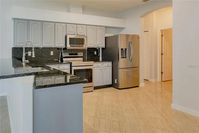 a kitchen with stainless steel appliances granite countertop a refrigerator a stove top oven a sink and dishwasher