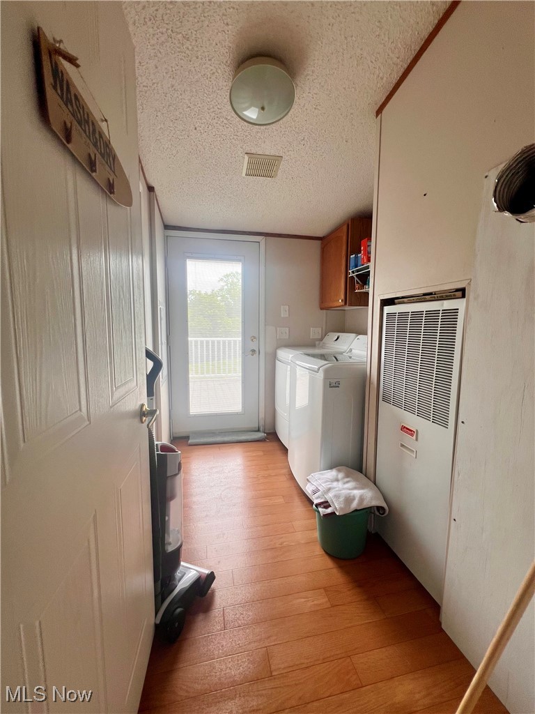 8548 Mount Carmel Rdg Road St. Marys, WV 26170 - Photo 26 of 30 Washroom featuring independent washer and dryer, a heating unit, light wood-type flooring, cabinet space, and a textured ceiling