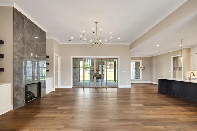 an empty room with wooden floor fireplace and windows