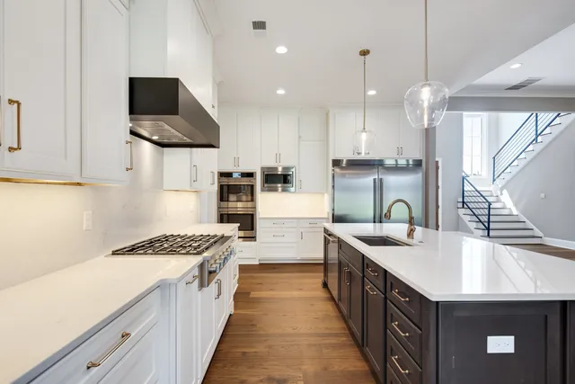 a kitchen with a refrigerator a sink and a stove top oven with wooden floor