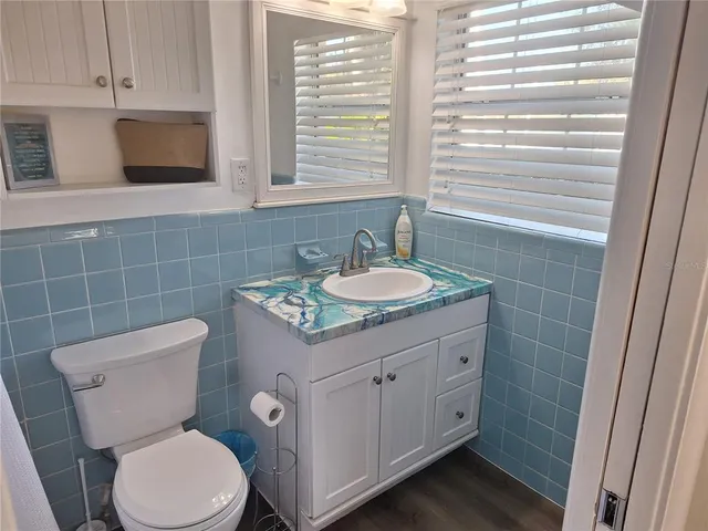 a bathroom with a granite countertop toilet a sink a mirror and a window