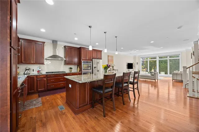 a kitchen with stainless steel appliances granite countertop a stove a refrigerator a sink a dining table and chairs with wooden floor