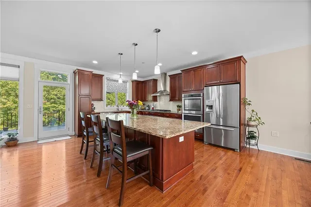 a kitchen with stainless steel appliances granite countertop a kitchen island hardwood floor and a sink