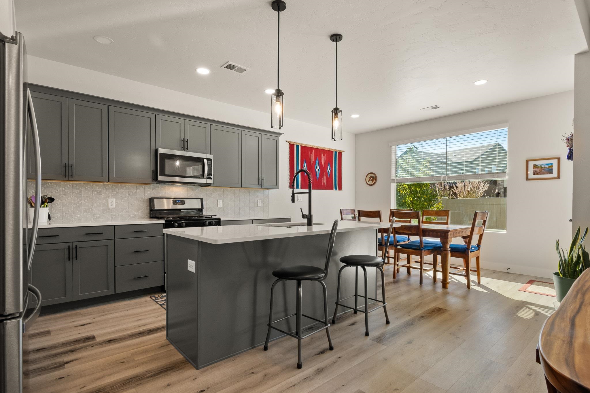 559 Hobbs Court Fruita, CO 81521 - Photo 12 of 40 a kitchen with stainless steel appliances granite countertop a stove top oven a sink dishwasher a dining table and chairs with wooden floor