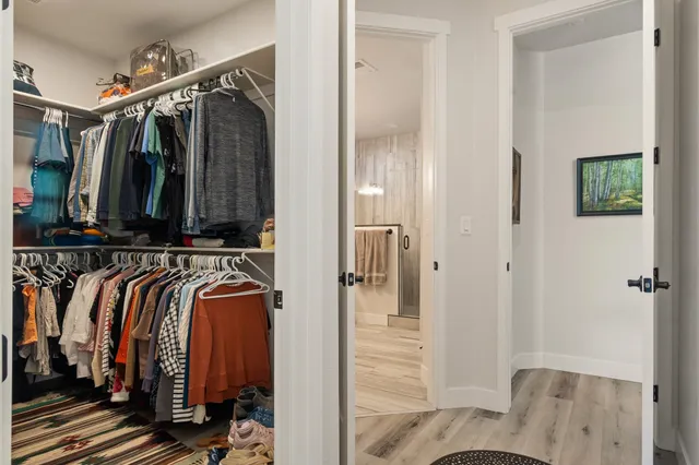 a view of walk in closet with clothes and shoes