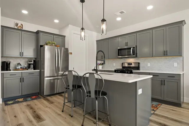 a kitchen with kitchen island granite countertop stainless steel appliances cabinets a sink and a counter top space