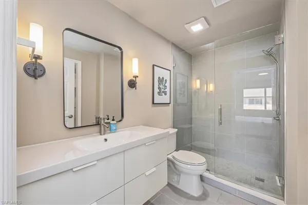 a bathroom with a toilet a sink a mirror and shower