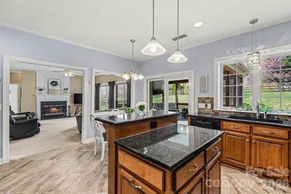 a kitchen with stainless steel appliances granite countertop a stove top oven a sink dishwasher a dining table and chairs with wooden floor