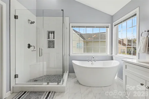 a bathroom with double vanity sinks a large mirror and a bathtub