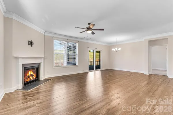 a view of an empty room with wooden floor fireplace and a window