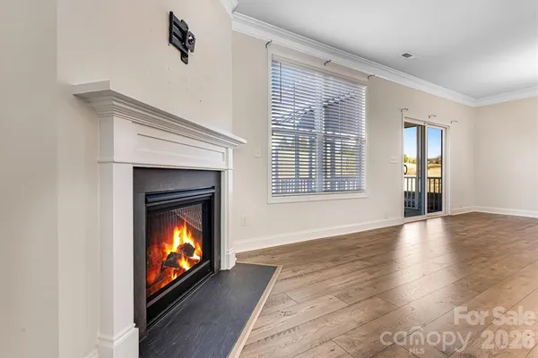 a view of an empty room with wooden floor fireplace and windows