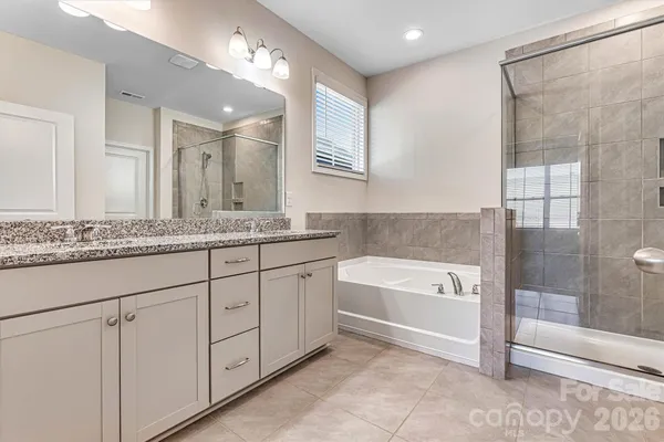 a spacious bathroom with a granite countertop sink mirror and bathtub