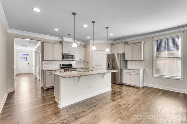 a kitchen with stainless steel appliances kitchen island granite countertop a stove a refrigerator a sink a oven and a refrigerator with wooden floor