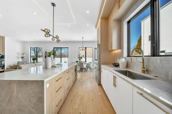 a large kitchen with kitchen island a large counter top a sink a large window and stainless steel appliances