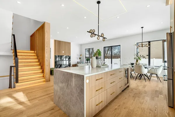 a view of a kitchen with kitchen island stainless steel appliances a table and chairs in it
