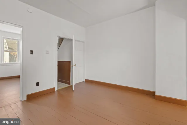 an empty room with wooden floor & closet area