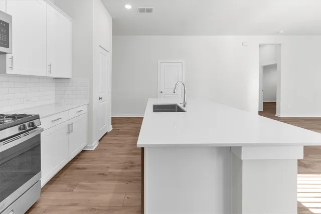 a kitchen with stainless steel appliances white cabinets and a stove top oven