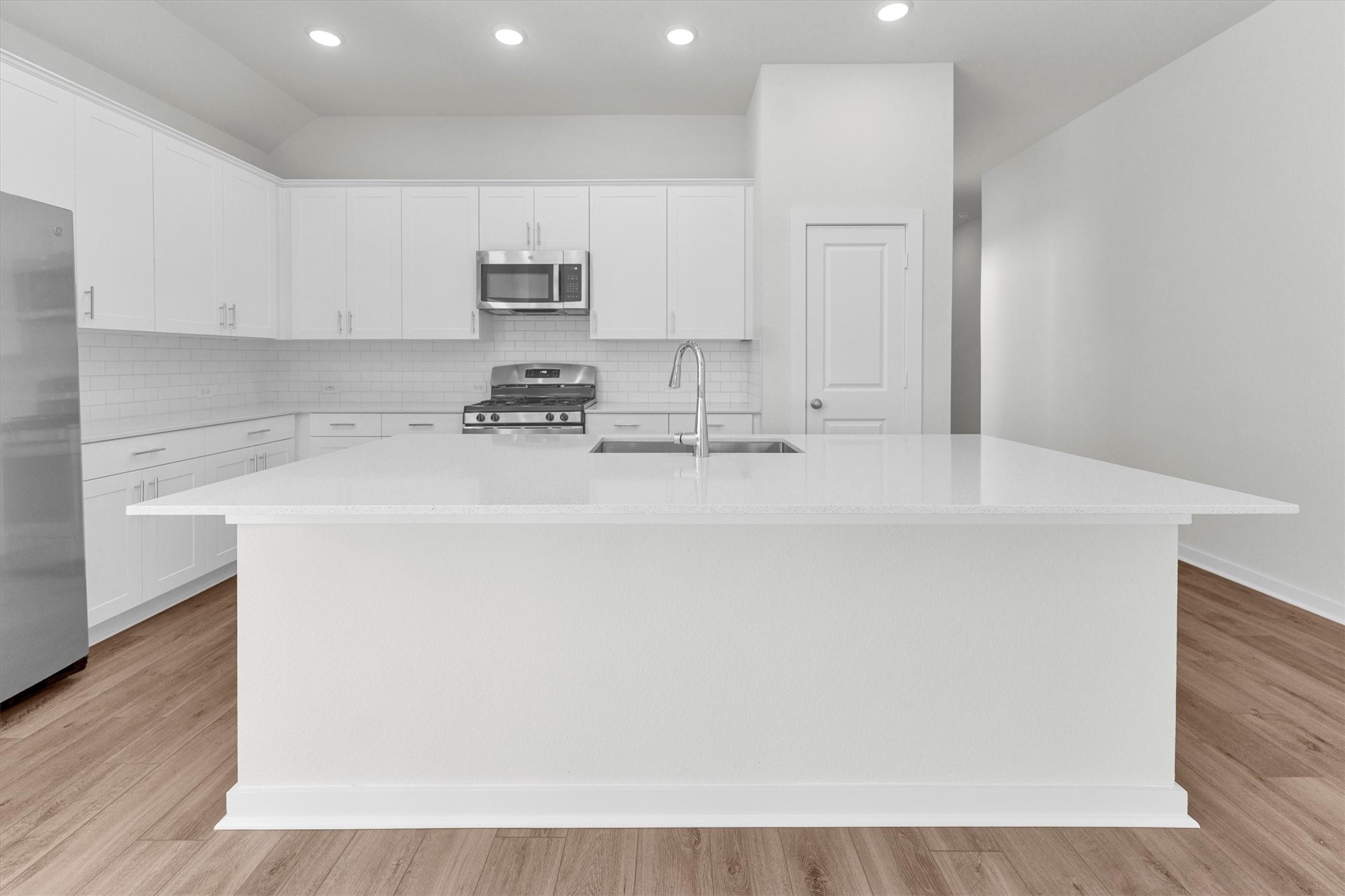 16914 Tulip Row Lane Cypress, TX 77429 - Photo 19 of 48 a kitchen with stainless steel appliances a sink a stove a microwave a sink a refrigerator with white cabinets and wooden floor
