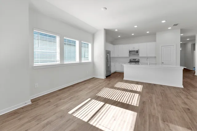an empty room with wooden floor ceiling fan and windows
