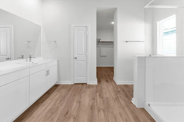 a spacious bathroom with a double vanity sink a mirror and a shower