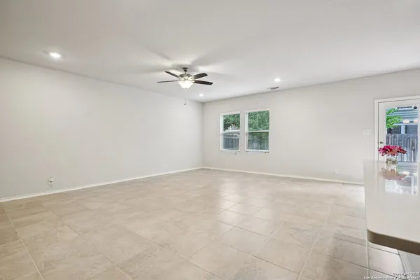 an empty room with windows and chandelier fan