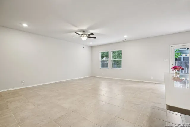 an empty room with windows and chandelier fan