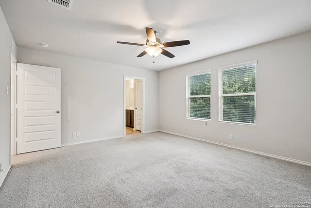 an empty room with windows and fan