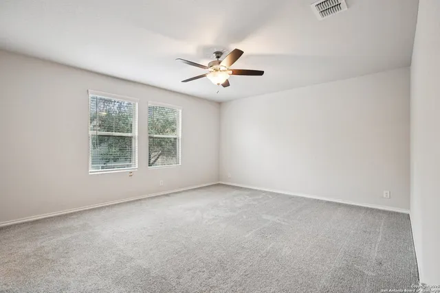 an empty room with a window and a ceiling fan