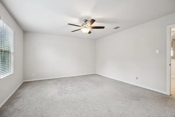 an empty room with chandelier fan and windows