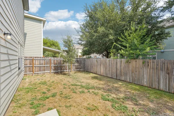 a view of backyard with wooden fence and trees
