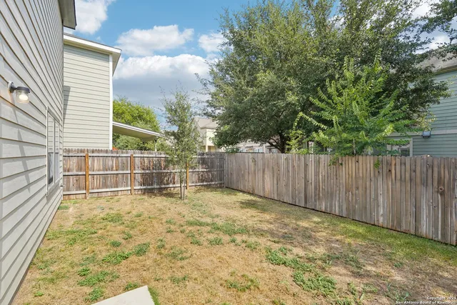 a view of backyard with wooden fence and trees