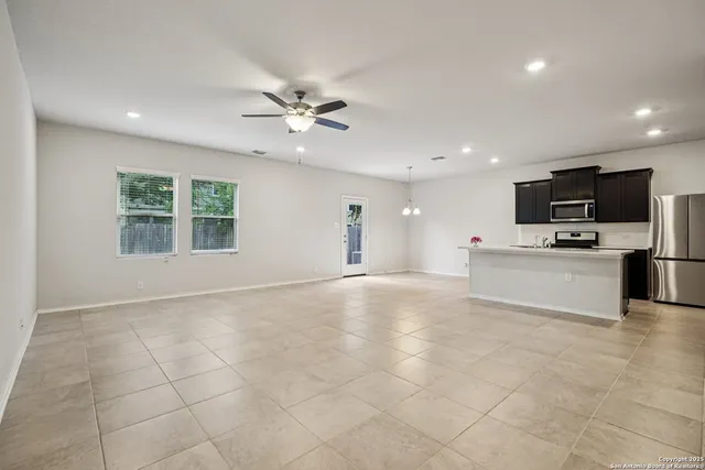 a view of kitchen with stainless steel appliances kitchen island granite countertop a stove top oven a sink a refrigerator with grey cabinets and glass door