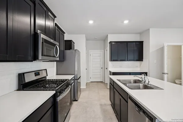 a kitchen with stainless steel appliances granite countertop a sink stove microwave and refrigerator
