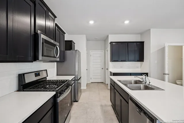 a kitchen with stainless steel appliances granite countertop a sink stove microwave and refrigerator