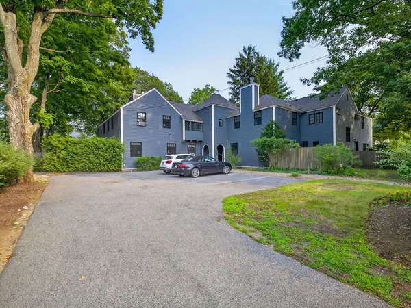 a front view of a house with a yard and a large tree