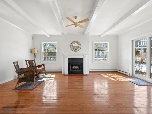 a view of an empty room with wooden floor fireplace and a window