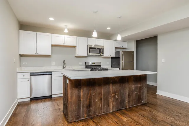 a large kitchen with stainless steel appliances granite countertop a stove a sink dishwasher and a refrigerator with wooden floor