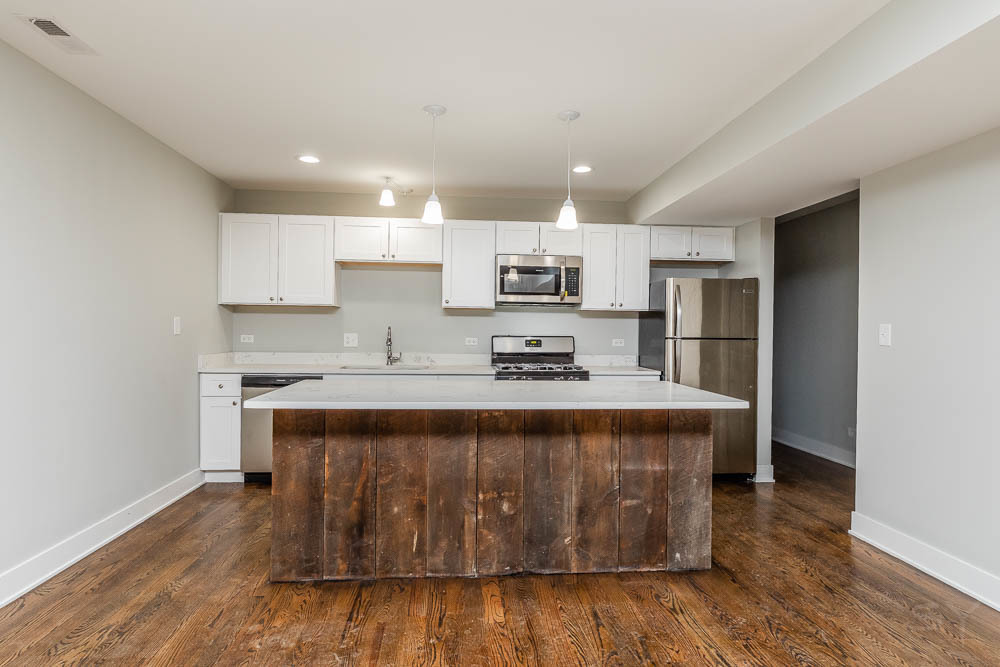 2109 West 18th Place Chicago, IL 60608 - Photo 4 of 63 a large kitchen with stainless steel appliances granite countertop a stove a sink dishwasher and a refrigerator with wooden floor