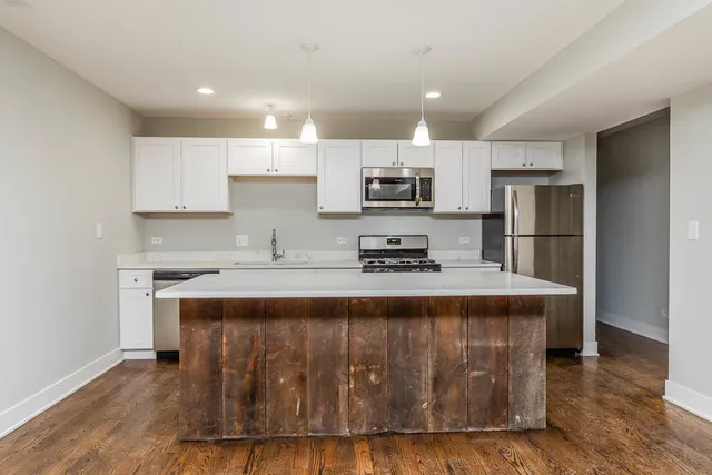 a open kitchen with kitchen island a sink dishwasher a stove and a refrigerator with wooden floor